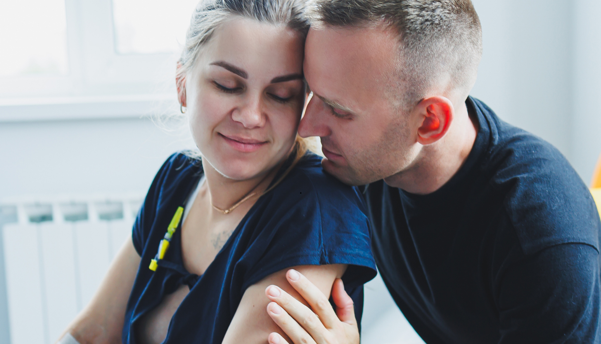 A pregnant woman being comforted by her partner